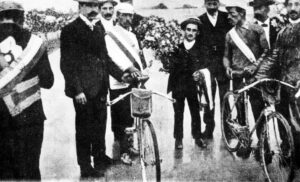 Omschrijving: Wielrennen, Tour de France 1904. De huldiging van de winnaars o.a. Hippolyte Aucouturier en Maurice Garin. De eerste vier renners van het klassement worden gediskwalificeert nadat fraude, vechtpartijen, en met kopspijkers strooiende supporters een normaal koersverloop onmogelijk hadden gemaakt. Parijs 1904